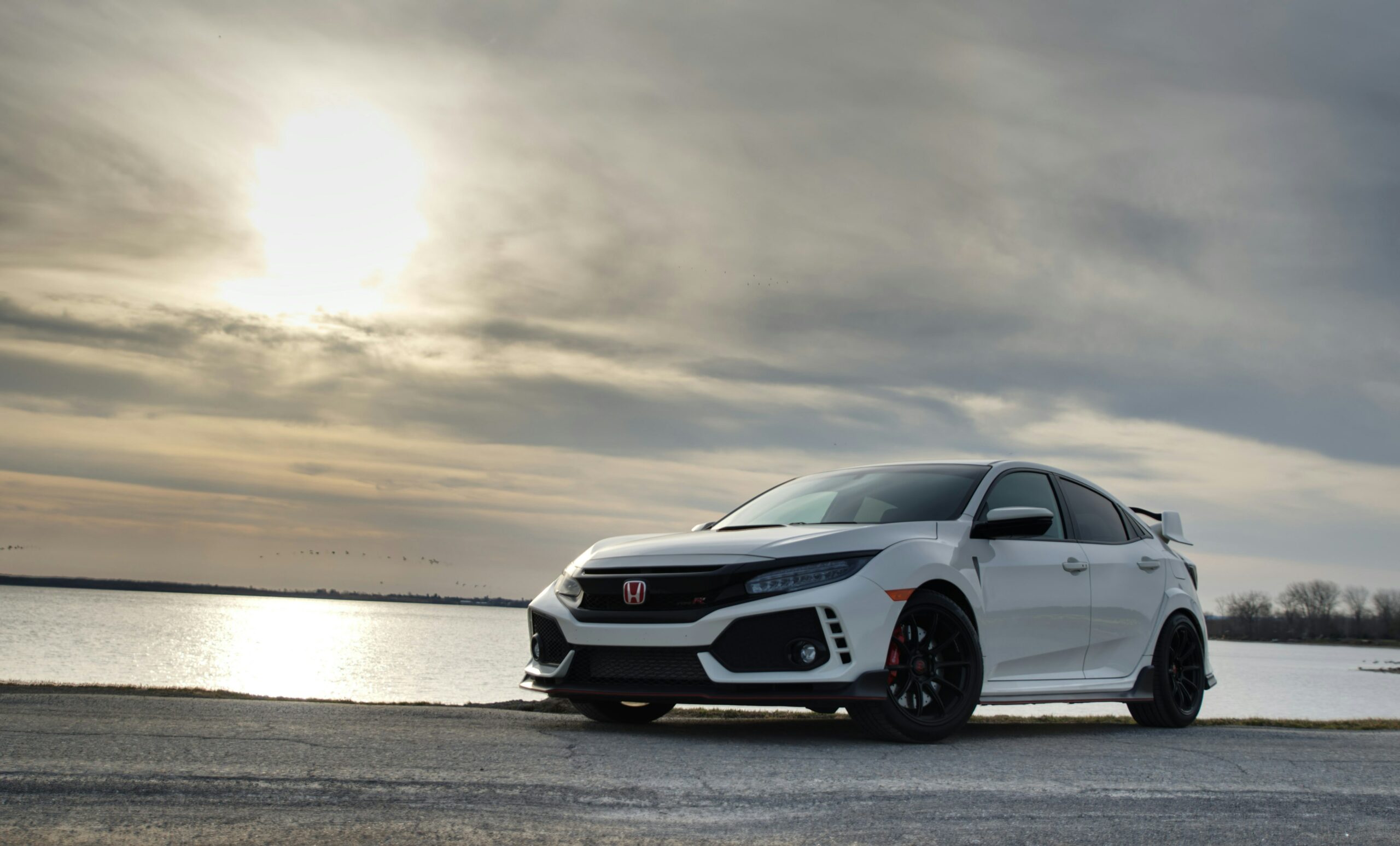 Hvid Honda Civic Type R parkeret ved vandet i solnedgang
