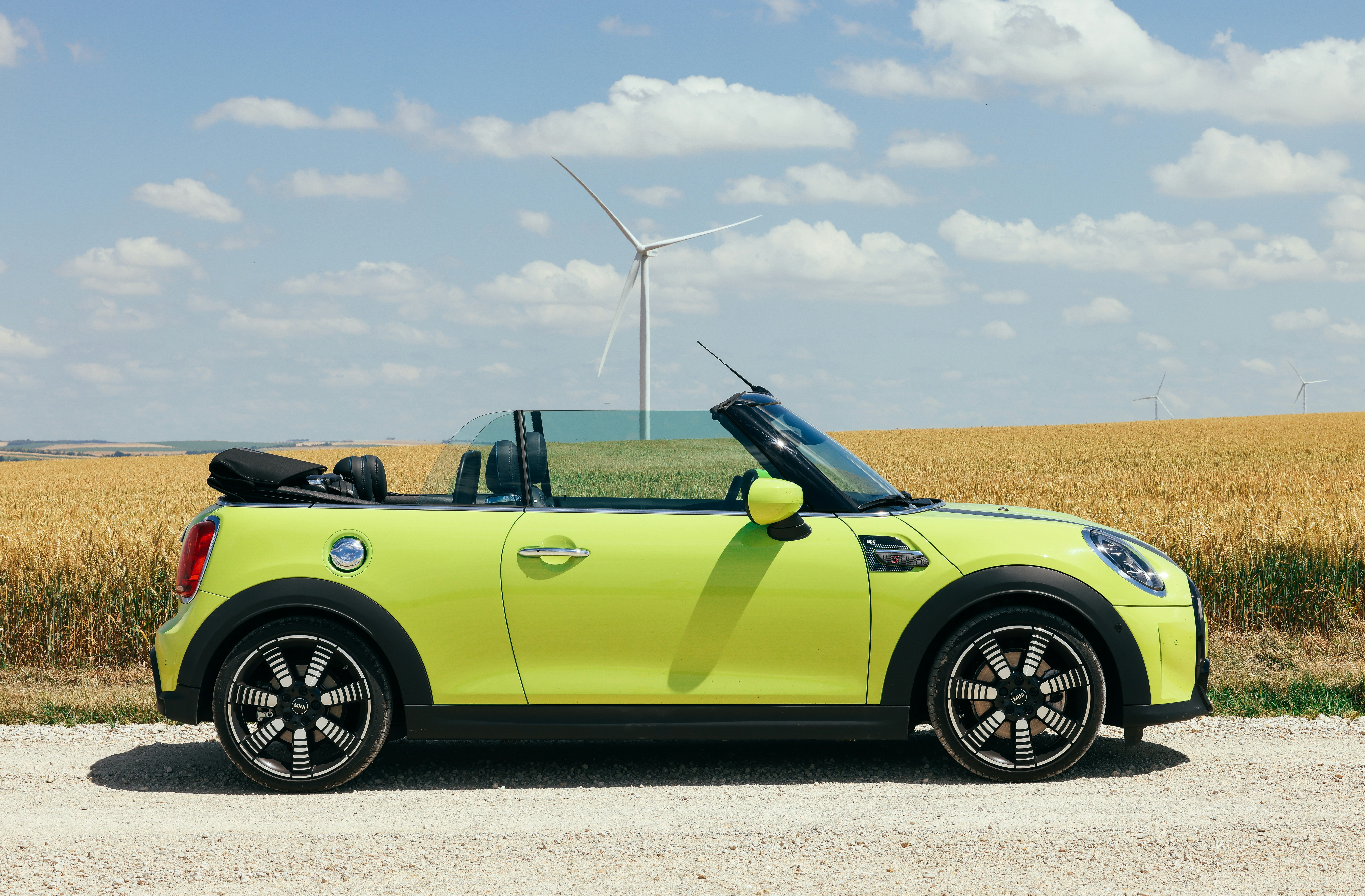 Grøn MINI Cabriolet ved en mark med vindmøller.