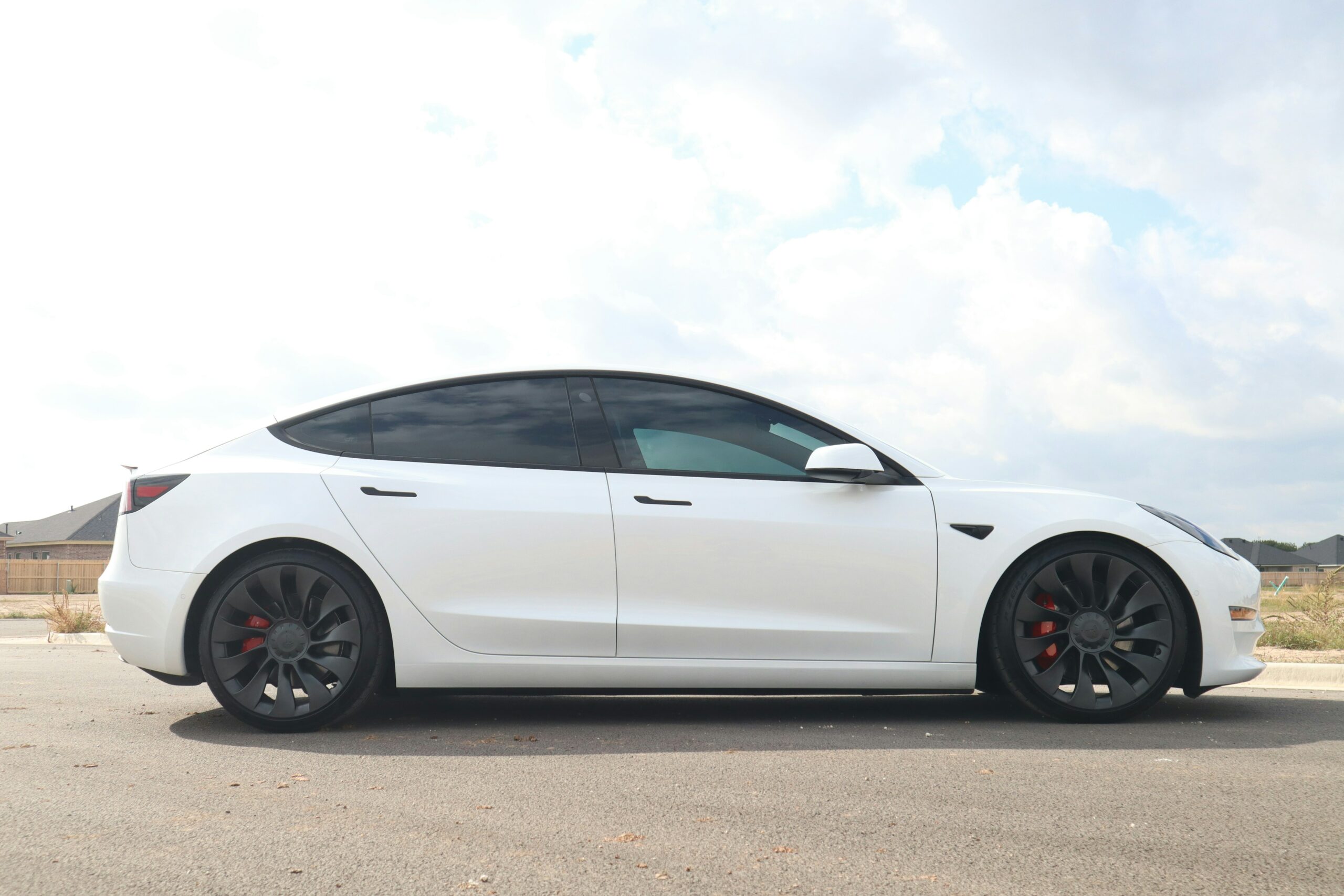 Hvid Tesla Model 3 parkeret på en vej.