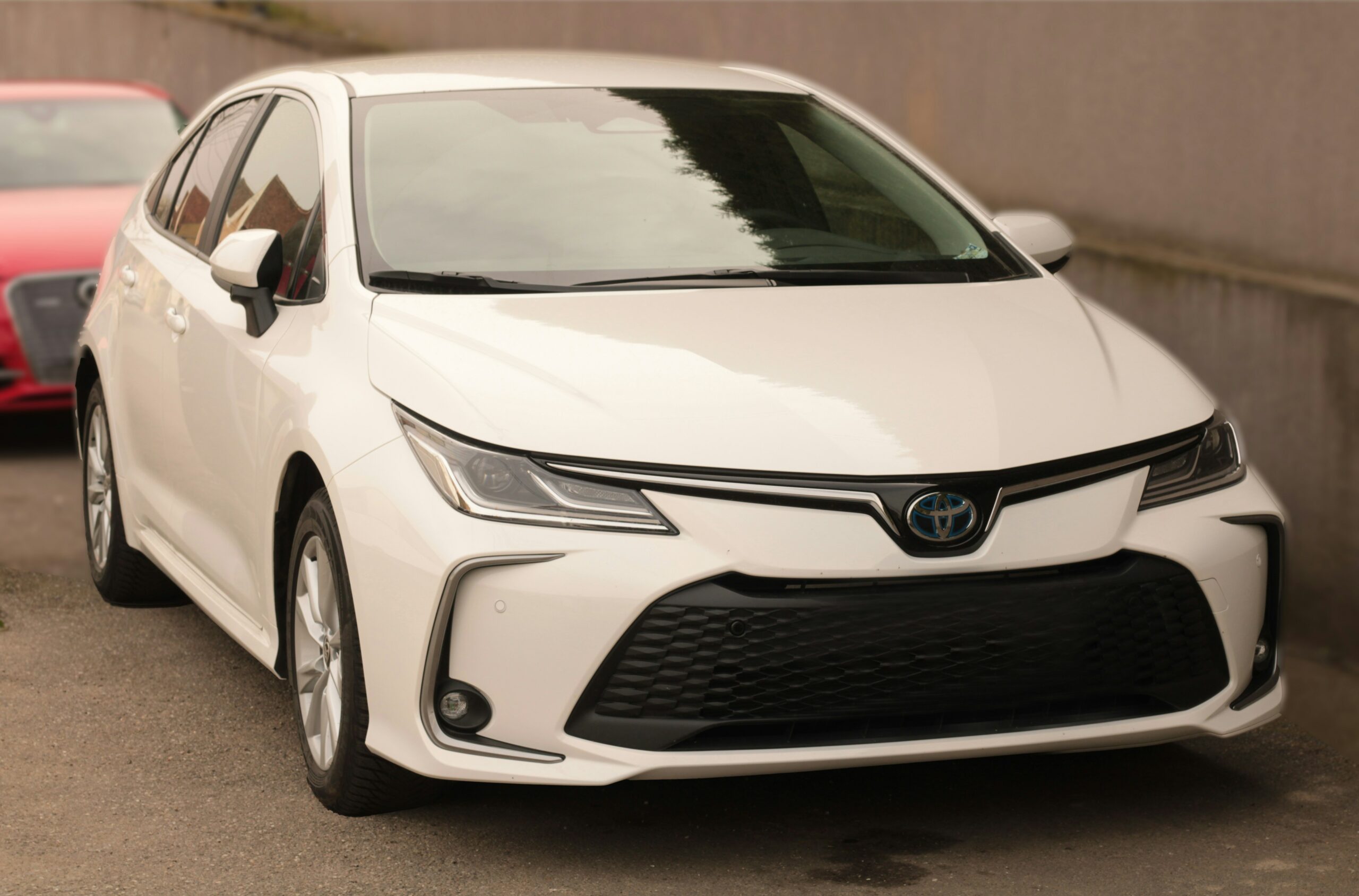 Hvid Toyota Corolla Hybrid parkeret udendørs.