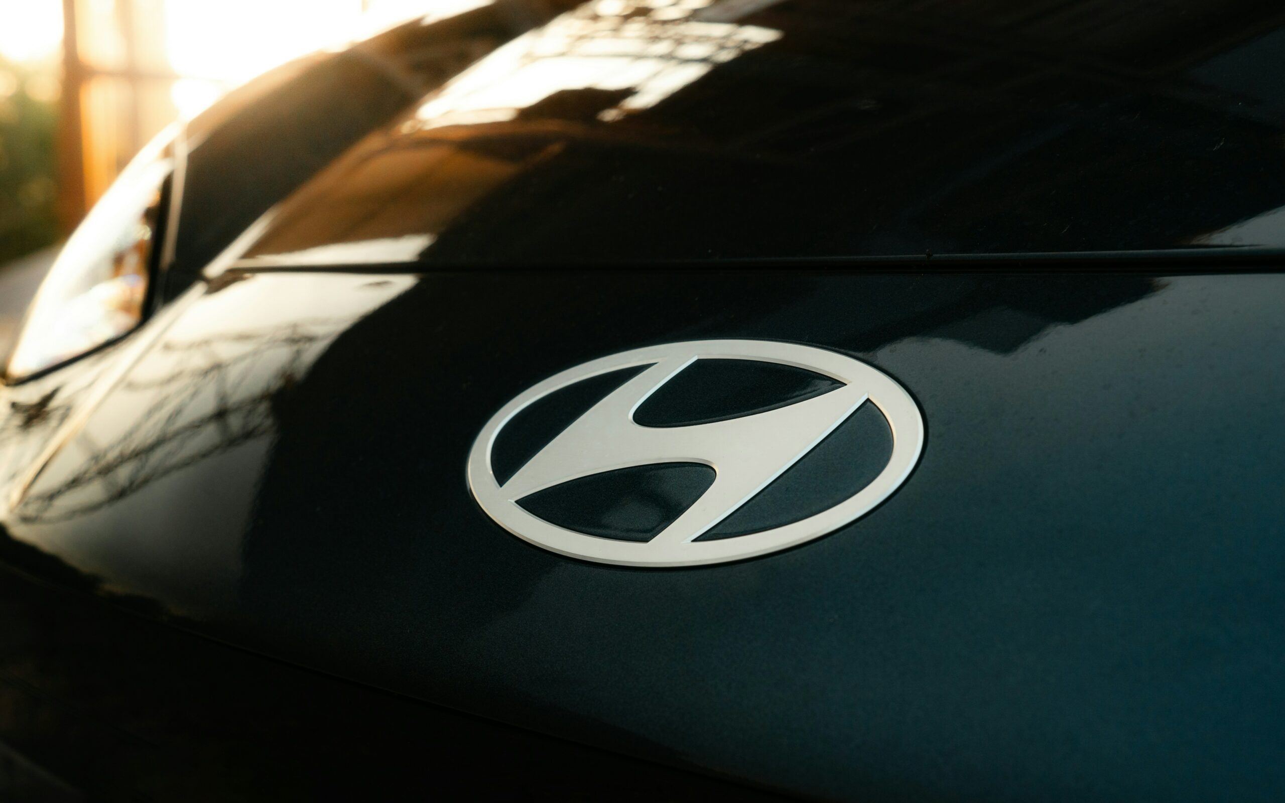 Nærbillede af Hyundai-logo på mørk bil i solnedgang